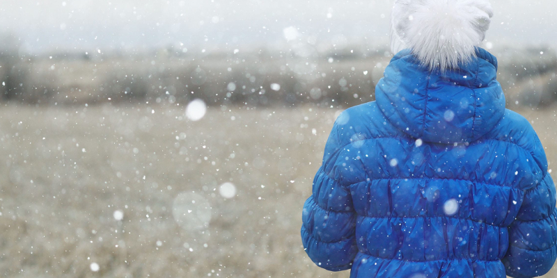 An Image of A Woman Wearing Blue Water Proof Jacket And White Scorf In A Winter Season.