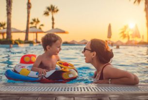 A Cute Little Boy Sitting In Pool Float & Busy Chatting With His Mom In The Pool.