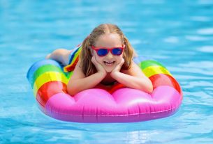 A Cute Adorable Little Girl Wearing Sun Glasses Giving Pose For The Camera From The Pool Float.