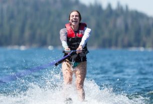 A Young Female Waterskier moving slow in splashes of water at a sunny day.