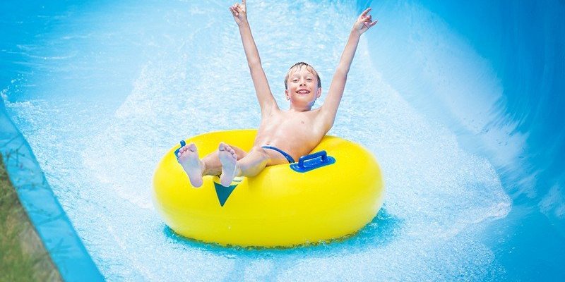 A Small Boy Enjoying Water Slider.