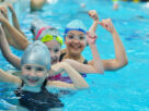 Three Happy Kids Starring At The Camera While Swimming.