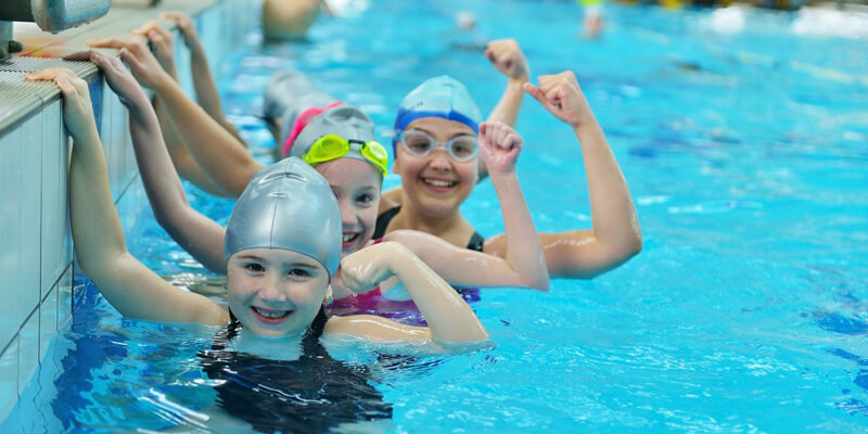 Three Happy Kids Starring At The Camera While Swimming.