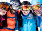 Two pair of couples in their winter suit standing in snow with their sport goggles