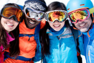 Two pair of couples in their winter suit standing in snow with their sport goggles