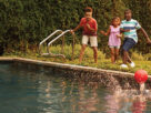 Three kids are shown in the picture playing with a ball in a swimming pool