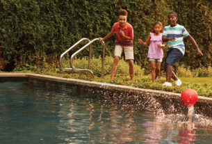Three kids are shown in the picture playing with a ball in a swimming pool