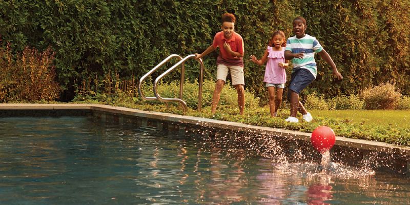 Three kids are shown in the picture playing with a ball in a swimming pool